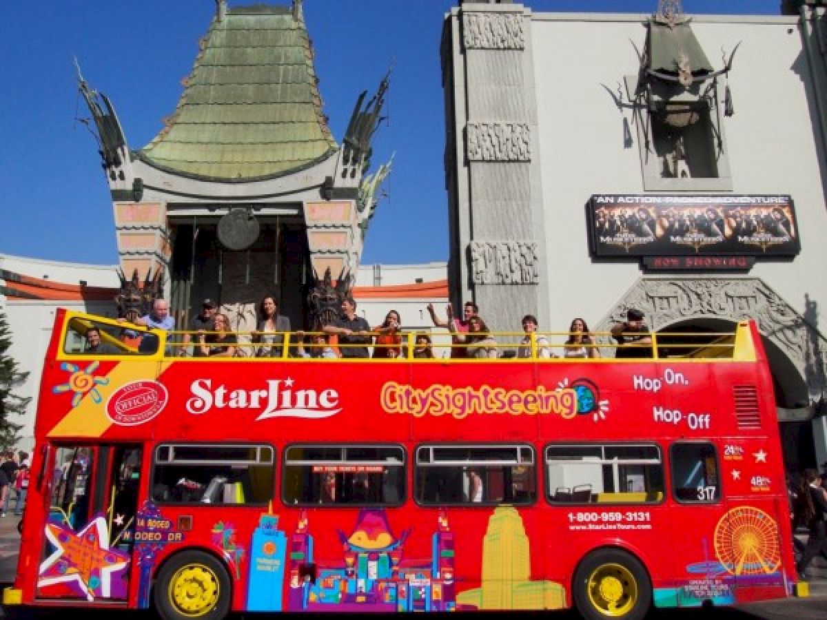 A red double-decker CitySightseeing bus in front of a building with tourists on top, labeled 