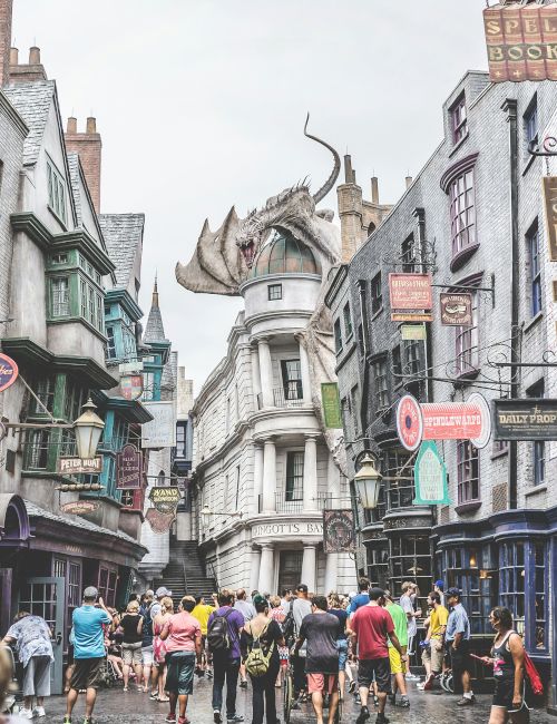 A crowded street with people walking, surrounded by old-style buildings with various shop signs, and a dragon sculpture on top of a building.